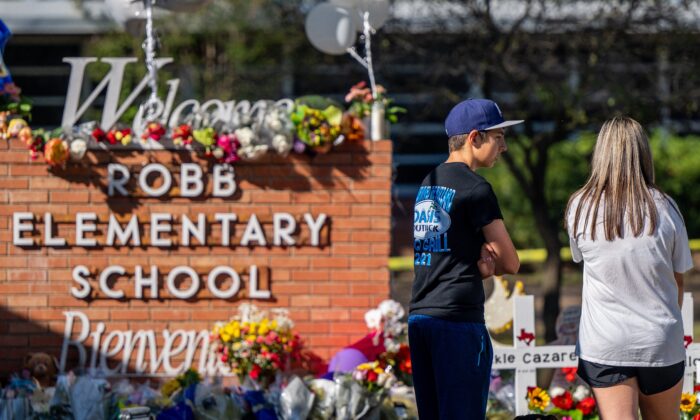 Young adults stand looking at a memorial at Robb Elementary School following a mass shooting in Uvalde, Texas, on May 26, 2022. (Brandon Bell/Getty Images)