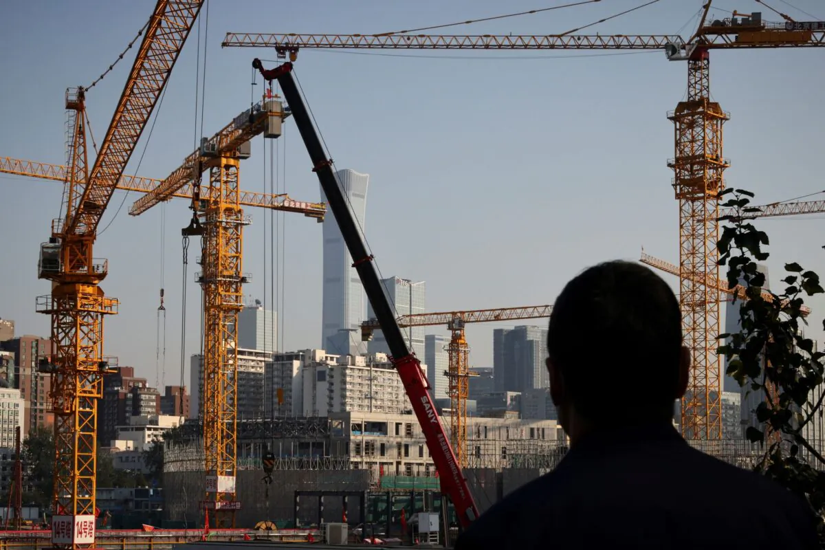 A person looks towards cranes in front of the skyline of the Central Business District (CBD) in Beijing on Oct. 18, 2021. (Thomas Peter/Reuters)