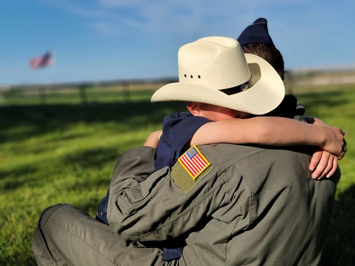 An Air Force father returns home from work and receives a hug from his son in an Iowa field. (Courtesy Airmen for Religious Freedom) 
