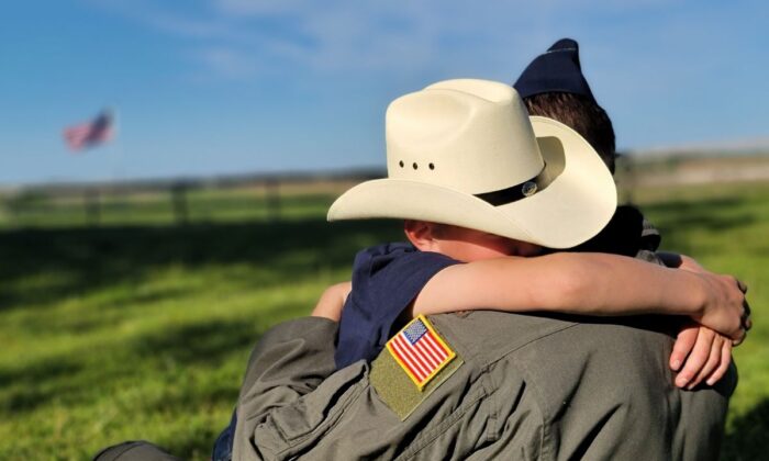 An Air Force father returns home from work and receives a hug from his son in an Iowa field. (Courtesy Airmen for Religious Freedom) 