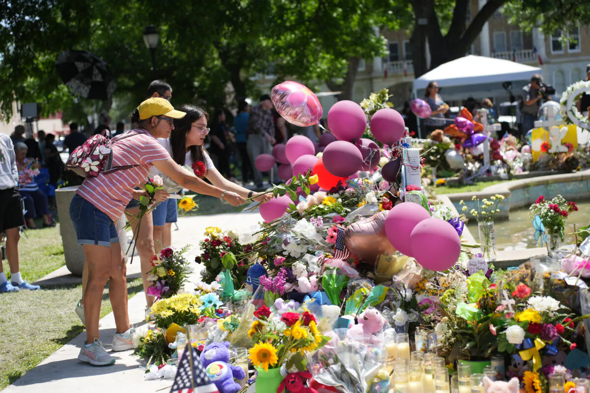 People place flowers at a makeshift memorial for the 21 victims of an elementary school mass shooting in the town square in Uvalde, Texas, on May 29, 2022. (Charlotte Cuthbertson/The Epoch Times)