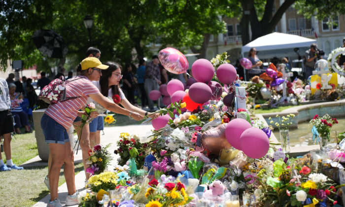 People place flowers at a makeshift memorial for the 21 victims of an elementary school mass shooting in the town square in Uvalde, Texas, on May 29, 2022. (Charlotte Cuthbertson/The Epoch Times)