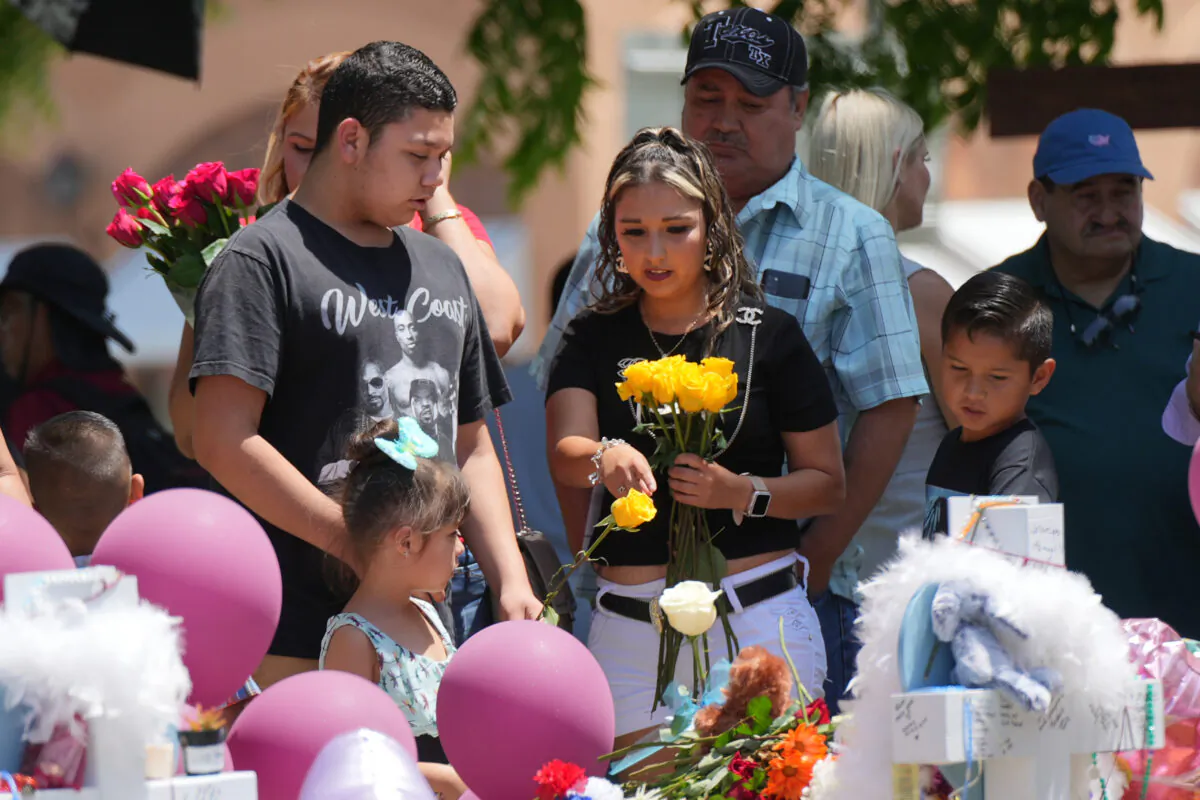 People visit a makeshift memorial for the 21 victims of an elementary school mass shooting in the town square in Uvalde, Texas, on May 29, 2022. (Charlotte Cuthbertson/The Epoch Times)