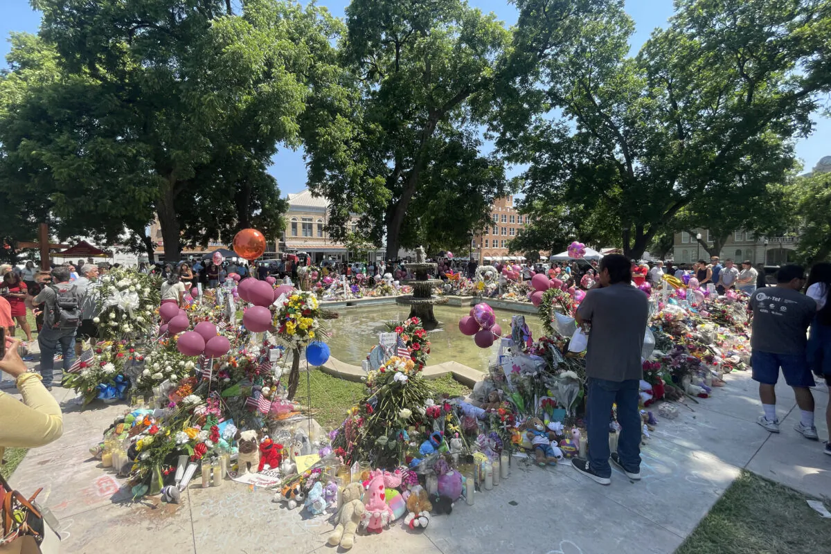 People visit a makeshift memorial for the 21 victims of an elementary school mass shooting in the town square in Uvalde, Texas, on May 29, 2022. (Charlotte Cuthbertson/The Epoch Times)