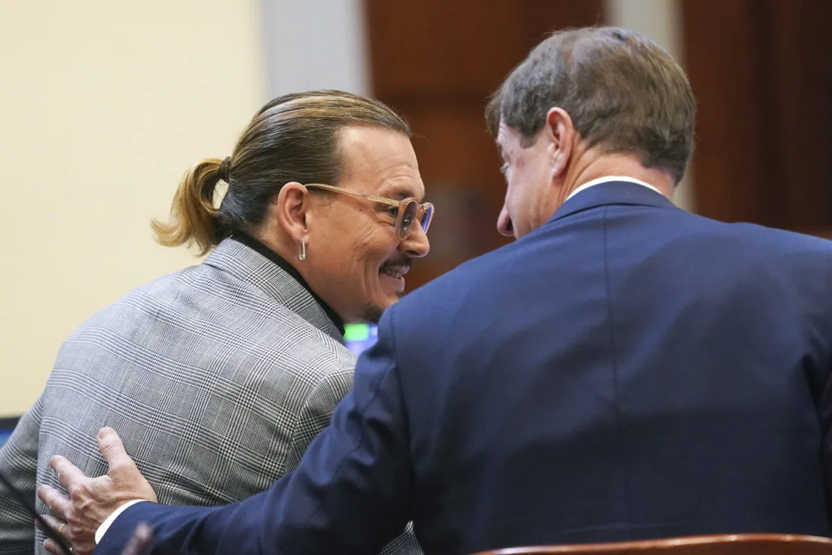 Actor Johnny Depp speaks with his legal team in the courtroom at the Fairfax County Circuit Courthouse in Fairfax, Va., on May 19, 2022. (Shawn Thew/Pool photo via AP)