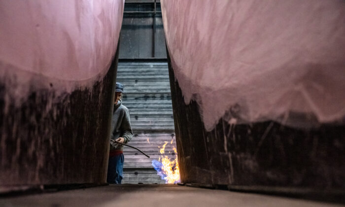 A worker uses a gas burner to prepare a casting mold at a foundry in Krefeld, Germany, on April 21, 2022. (Sascha Schuermann/Getty Images)