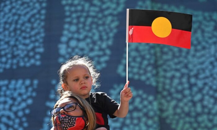 2022 年 1 月 26 日，悉尼的澳大利亚日，一名年轻女孩高举澳大利亚土著国旗。（Steven Saphore/Getty Images）