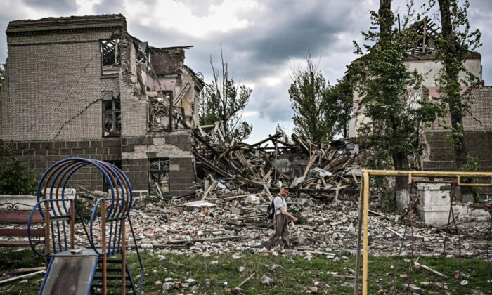 Mężczyzna idzie przed zniszczoną szkołą w mieście Bachmut, we wschodnim ukraińskim regionie Donbasu, 28 maja 2022 r. (Aris Messinis/AFP via Getty Images)