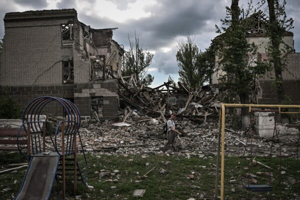 A man walks in front of a destroyed school in the city