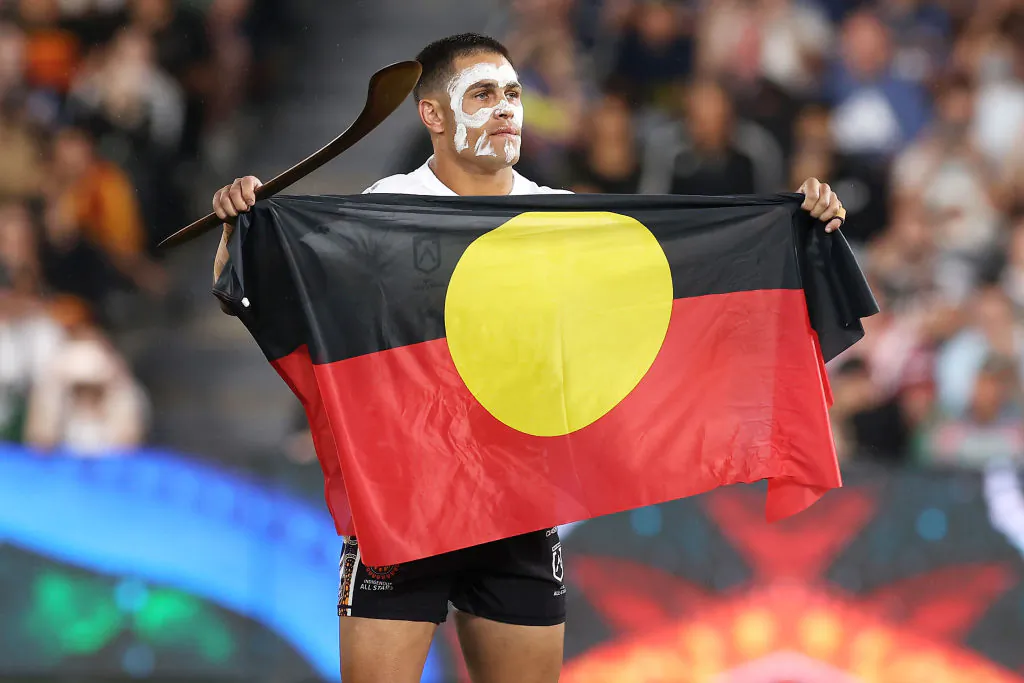 Will Smith of the Indigenous All Stars holds the The Australian Aboriginal flag during pre-match ceremony before the match between the Men's Indigenous All Stars and the Men's Maori All Stars at CommBank Stadium in Sydney, Australia, on Feb. 12, 2022. (Mark Kolbe/Getty Images)