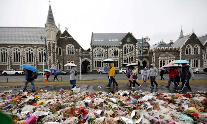 2019 年 4 月 5 日，新西兰克赖斯特彻奇植物园外，人们走过鲜花和悼念双胞胎清真寺大屠杀遇难者。（Sanka Vidanagama/AFP via Getty Images）
