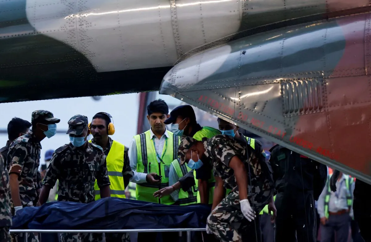Member of Nepal Army carries the body of a victim of the Tara Air passenger plane from the helicopter at the airport in Kathmandu, Nepal on May 30, 2022. (Navesh Chitrakar/Reuters)
