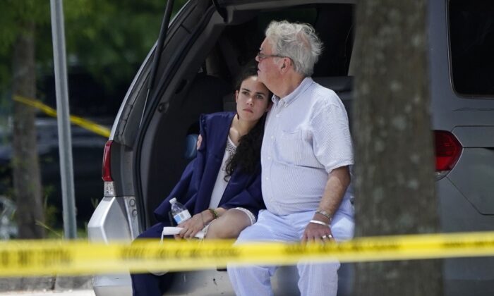 A man comforts a young woman wearing a graduation gown within the crime scene of a shooting at Xavier University in New Orleans, on May 31, 2022. (Gerald Herbert/AP Photo)