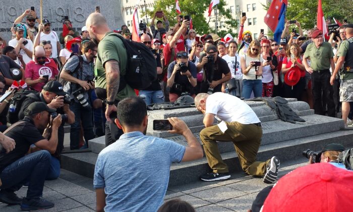 Veteran James Topp takes a knee in front of the Tomb of the Unknown Soldier in Ottawa on June 30, 2022. Topp walked 4,300 kilometres from Vancouver to protest against vaccine mandates. (Noé Chartier/The Epoch Times)