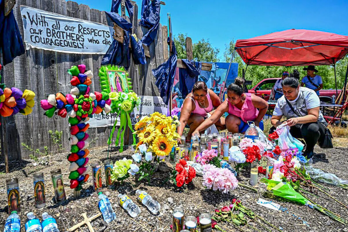 People place flowers and candles at a makeshift memorial where a tractor-trailer was discovered with deceased illegal immigrants inside, near San Antonio, Texas, on June 29, 2022. (Chandan Khanna/AFP via Getty Images)