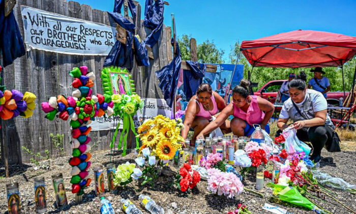 People place flowers and candles at a makeshift memorial where a tractor-trailer was discovered with deceased illegal immigrants inside, near San Antonio, Texas, on June 29, 2022. (Chandan Khanna/AFP via Getty Images)
