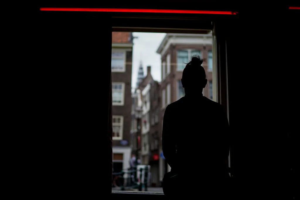 A sex worker waits for clients behind a window in the red light district of Amsterdam on July 1, 2020. (AFP via Getty Images/Kenzo Tribouillard)