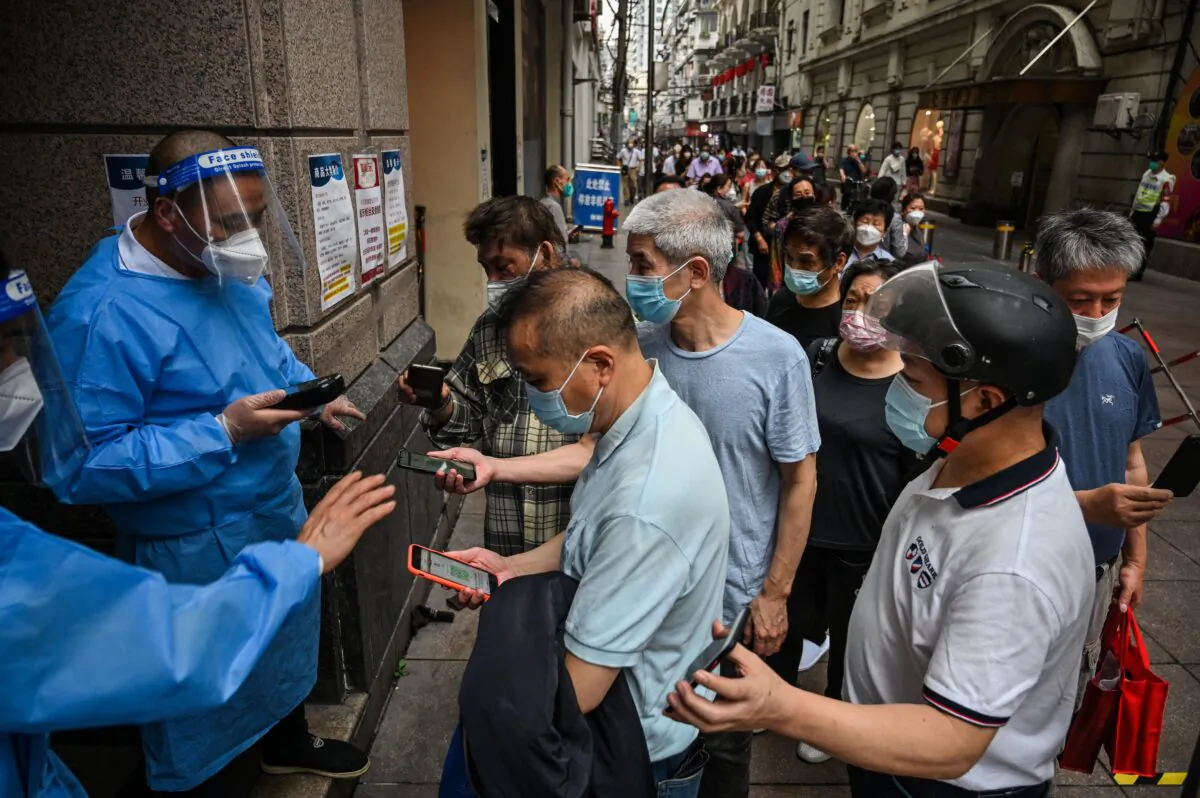 Workers scan QR health codes of people entering a shopping mall in the Huangpu district of Shanghai on June 1, 2022. (Hector Retamal/AFP via Getty Images)