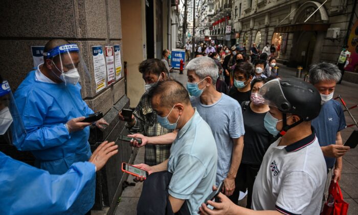 Workers scan QR health codes of people entering a shopping mall in the Huangpu district of Shanghai on June 1, 2022. (Hector Retamal/AFP via Getty Images)