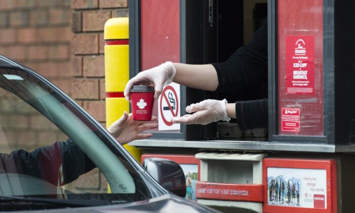A Tim Hortons employee hands out coffee from a drive-thru window to a customer in Mississauga, Ont., on March 17, 2020. (The Canadian Press/Nathan Denette)