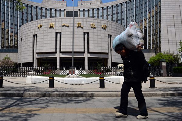 A Chinese migrant worker passes by the People's Bank of China in Beijing on May 1, 2013. (Mark Ralston/AFP)