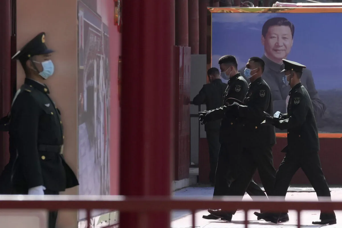 Chinese military personnel pass by a board displaying a photo of Chinese Communist Party leader Xi Jinping in Beijing on March 4, 2022, (AP Photo/Ng Han Guan)