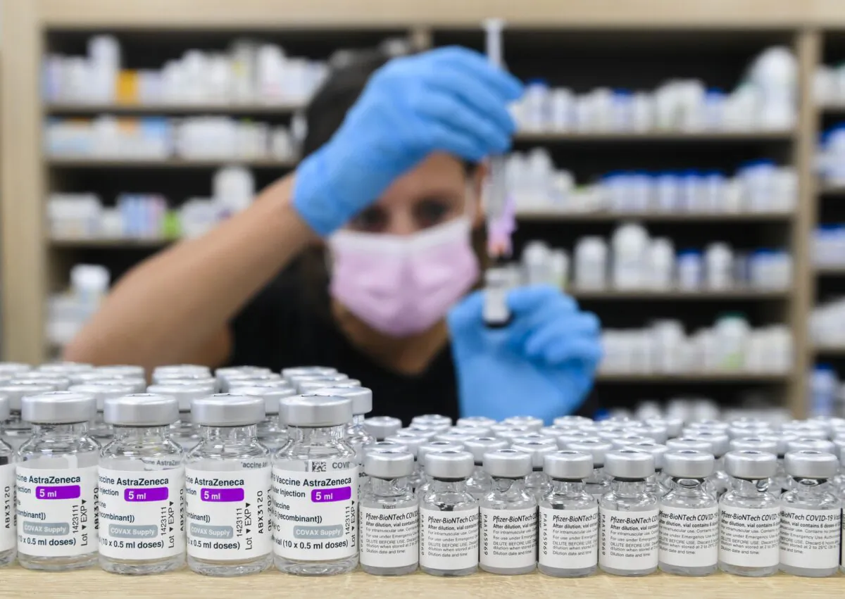 A pharmacist prepares a dose behind a counter lined with vials of COVID-19 vaccines, in Toronto on June 18, 2021. (The Canadian Press/Nathan Denette)