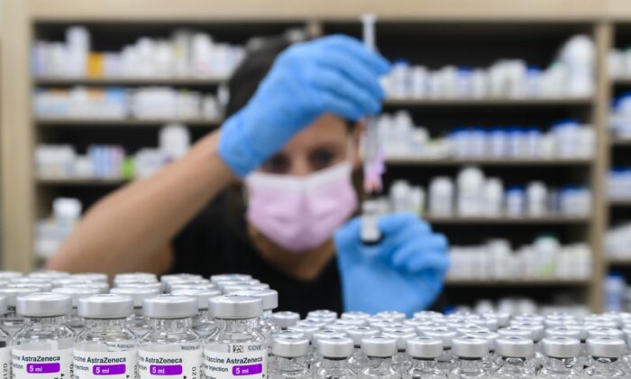 A pharmacist prepares a dose behind a counter lined with vials of COVID-19 vaccines, in Toronto on June 18, 2021. (The Canadian Press/Nathan Denette)