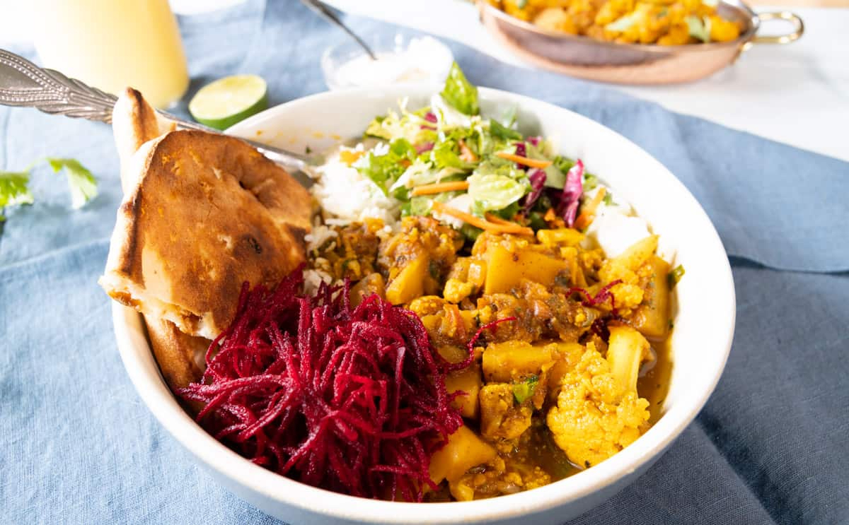 Aloo Gobi served in.a rice bowl with shredded beet and salad