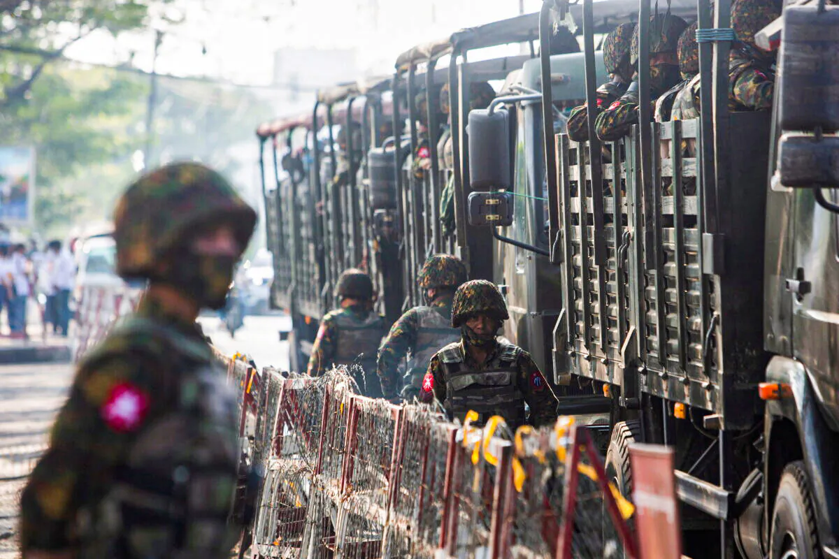 Soldiers stand next to military vehicles as people gather to protest against the military coup, in Yangon, Burma, on Feb. 15, 2021. (Stringer/Reuters)