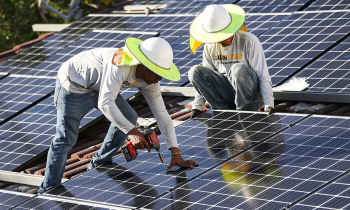 Roger Garbey (L) and Andres Hernandez, from the Goldin Solar company, install a solar panel system on the roof of a home a day after the Trump administration announced it will impose duties of as much as 30 percent on solar equipment made abroad, in Palmetto Bay, Fla., on Jan. 23, 2018. (Joe Raedle/Getty Images)