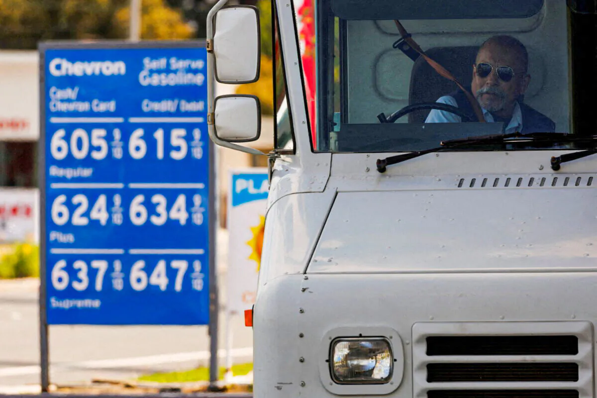A U.S. postal worker puts his seatbelt on after filing up his vehicle at a gas station in Garden Grove, Calif., on March 29, 2022. (Mike Blake/Reuters)