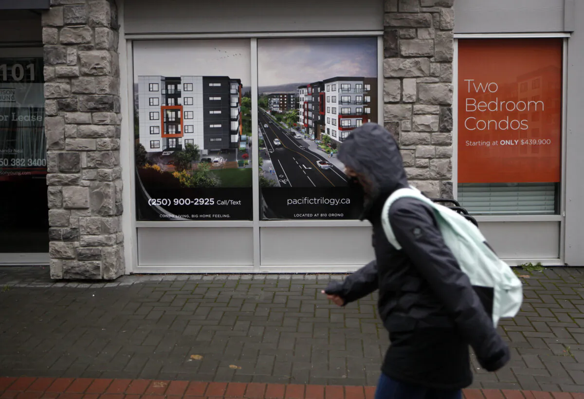 A person walks past a condo home sales sign in Langford, B.C., on Oct. 22, 2021. (The Canadian Press/Chad Hipolito)