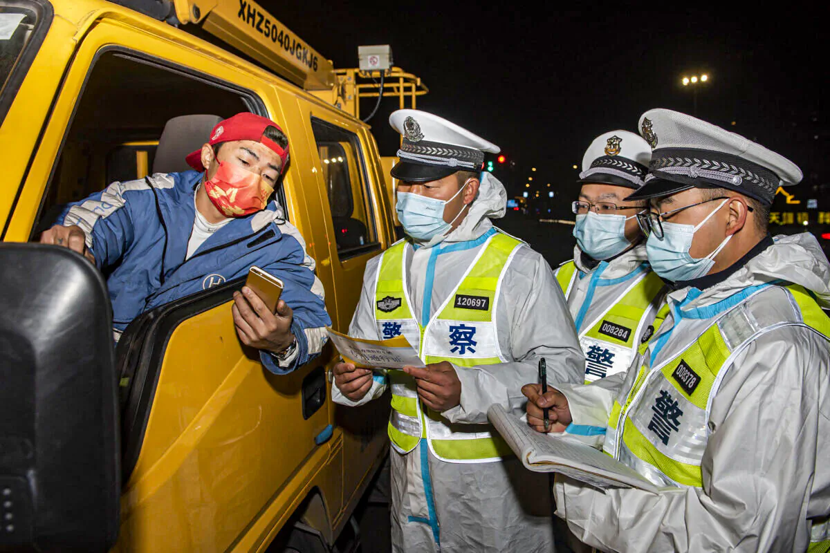 Police officers are checking information with a truck driver (L) at a checkpoint in Ningbo, Zhejiang Province, China, on Dec. 18, 2021. (STR/AFP via Getty Images)