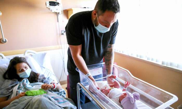 A father prepares to change the diaper of his newborn daughter as his wife looks on in a hospital in Apple Valley, California, on March 30, 2021. (Mario Tama/Getty Images)