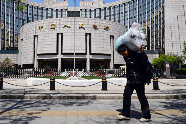 The picture shows a Chinese migrant worker passes by the People's Bank of China in Beijing, on May 1, 2013. (Mark Ralston/AFP)