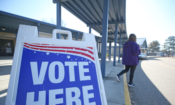A person walks past a sign during a runoff election for Louisiana governor at a polling station at Quitman High School in Quitman, La., on Nov. 16, 2019. (Matt Sullivan/Getty Images)