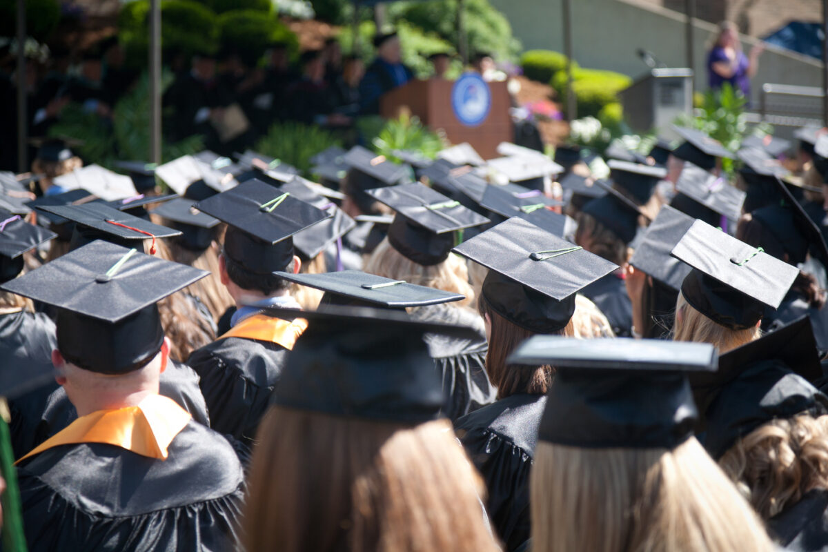 Students at an outdoor university commencement ceremony. (Dreamstime)