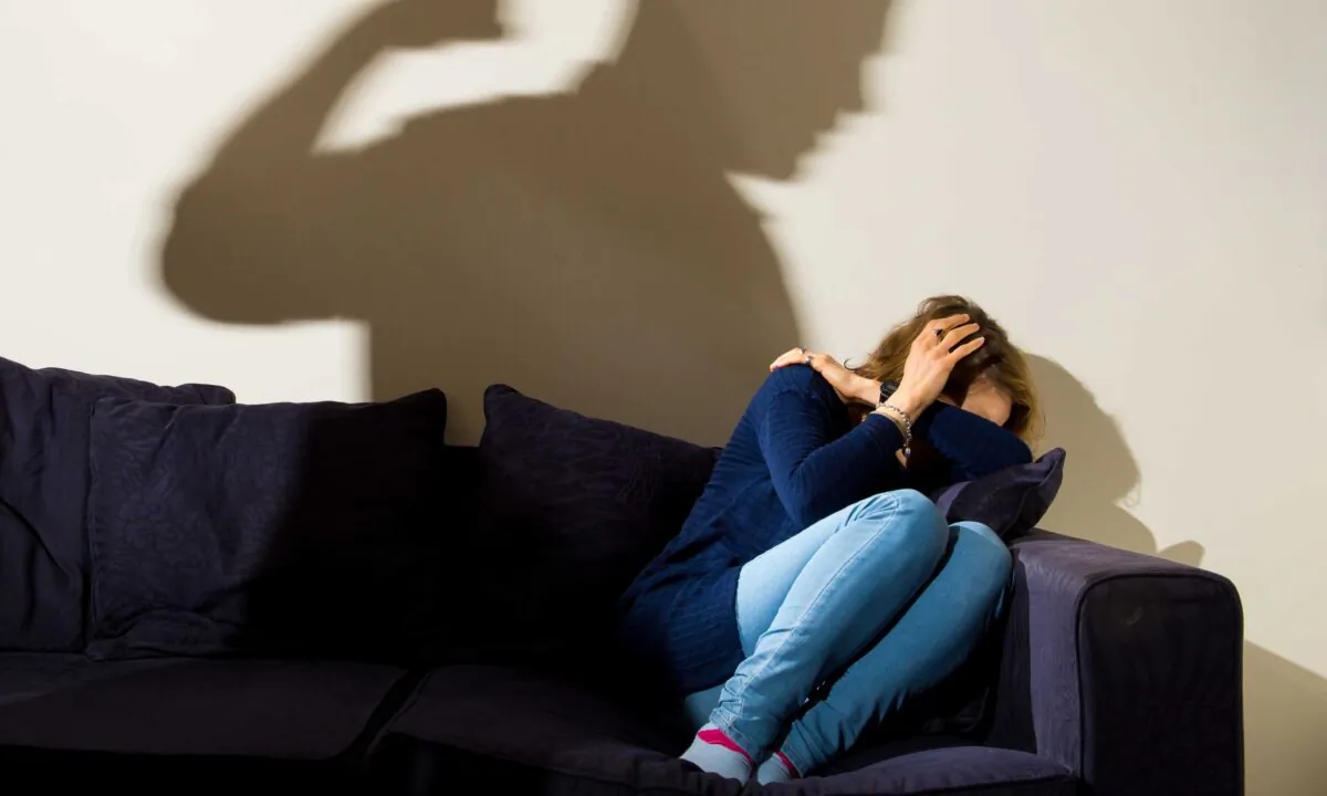 A model plays the part of a domestic abuse victim in the shadow of her abuser in London on March 9, 2015. (PA)