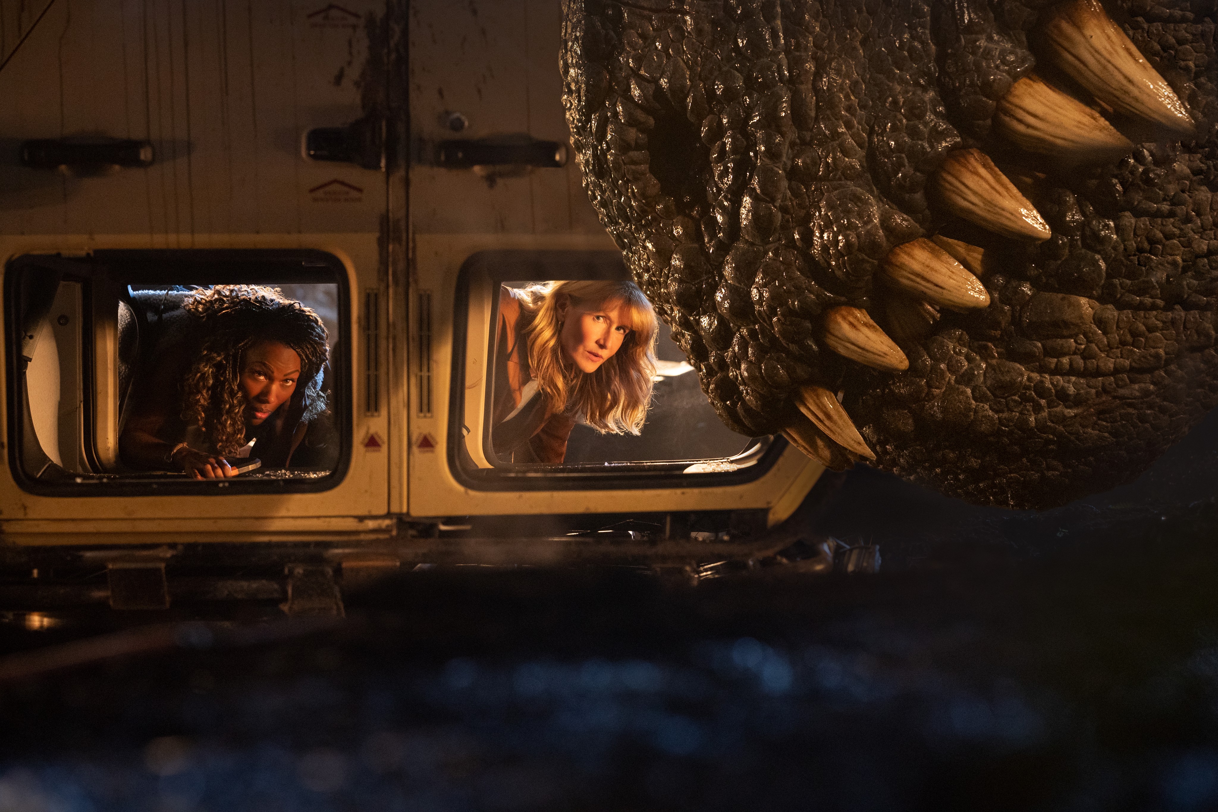 two women in an upsidedown car with a T. Rex in Jurassic World: Dominion