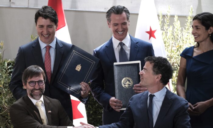 Prime Minister Justin Trudeau (back L) celebrates with California Gov. Gavin Newsom (C) and California Senior Climate Adviser Lauren Sanchez (back R), as Canada's Environment Minister Steven Guilbeault (front L) and California Senior Environmental Protection Agency Chief Jerod Blumenthal sign a memorandum of cooperation on climate change at the California Science Center outside the ninth Summit of the Americas, in Los Angeles on June 9, 2022. (Richard Vogel/AP Photo)