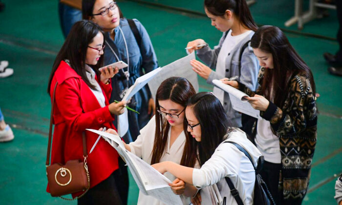 Young adults look at postings at a job fair at Shenyang Aerospace University in Shenyang, China's northeast Liaoning Province, on May 13, 2017. (STR/AFP/Getty Images)