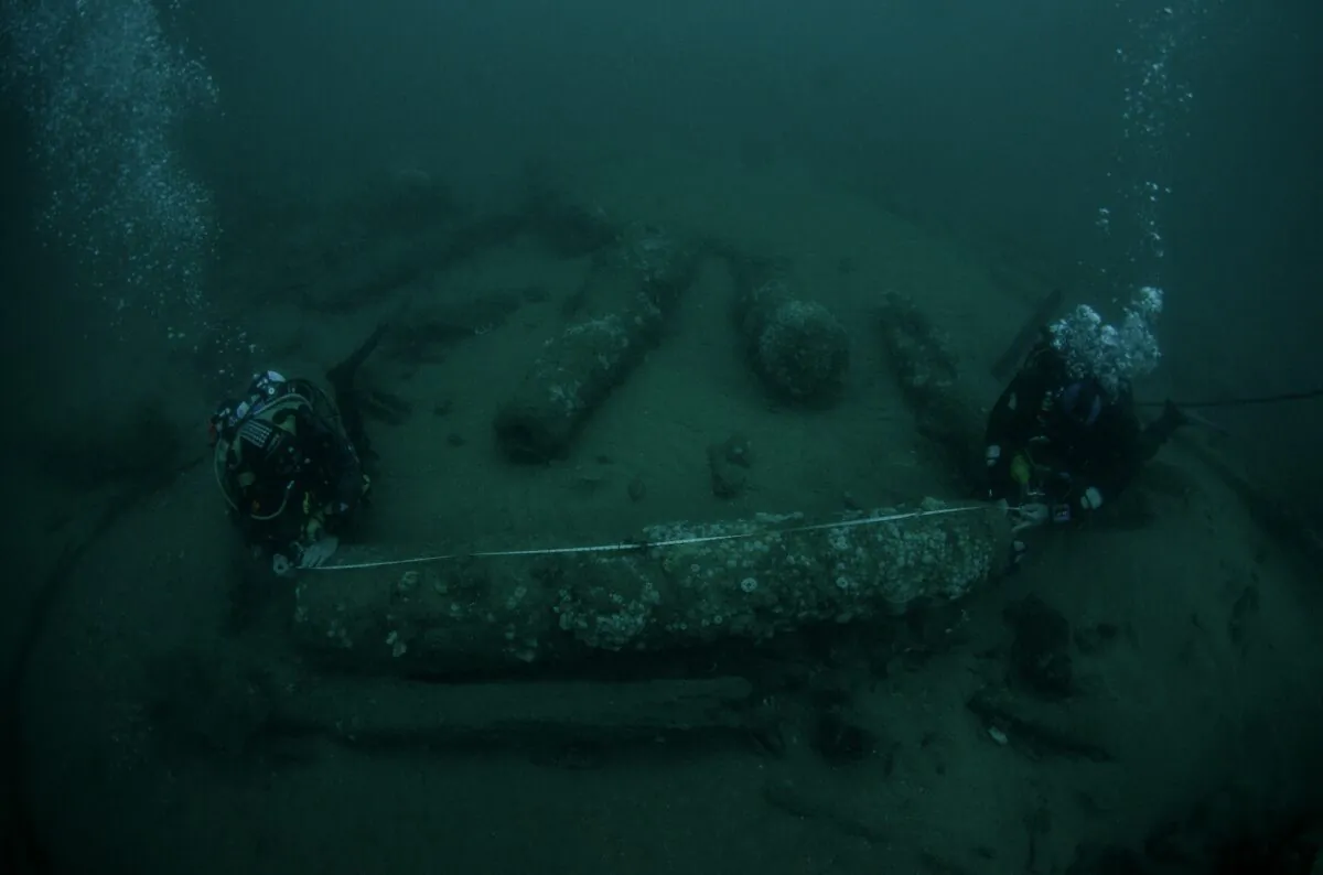 Brothers Julian and Lincoln Barnwell measuring a cannon near the wreck of HMS Gloucester, which was found off the coast of Norfolk, United Kingdom, in an undated photo issued on June 10, 2022. (Norfolk Historic Shipwrecks/PA)
