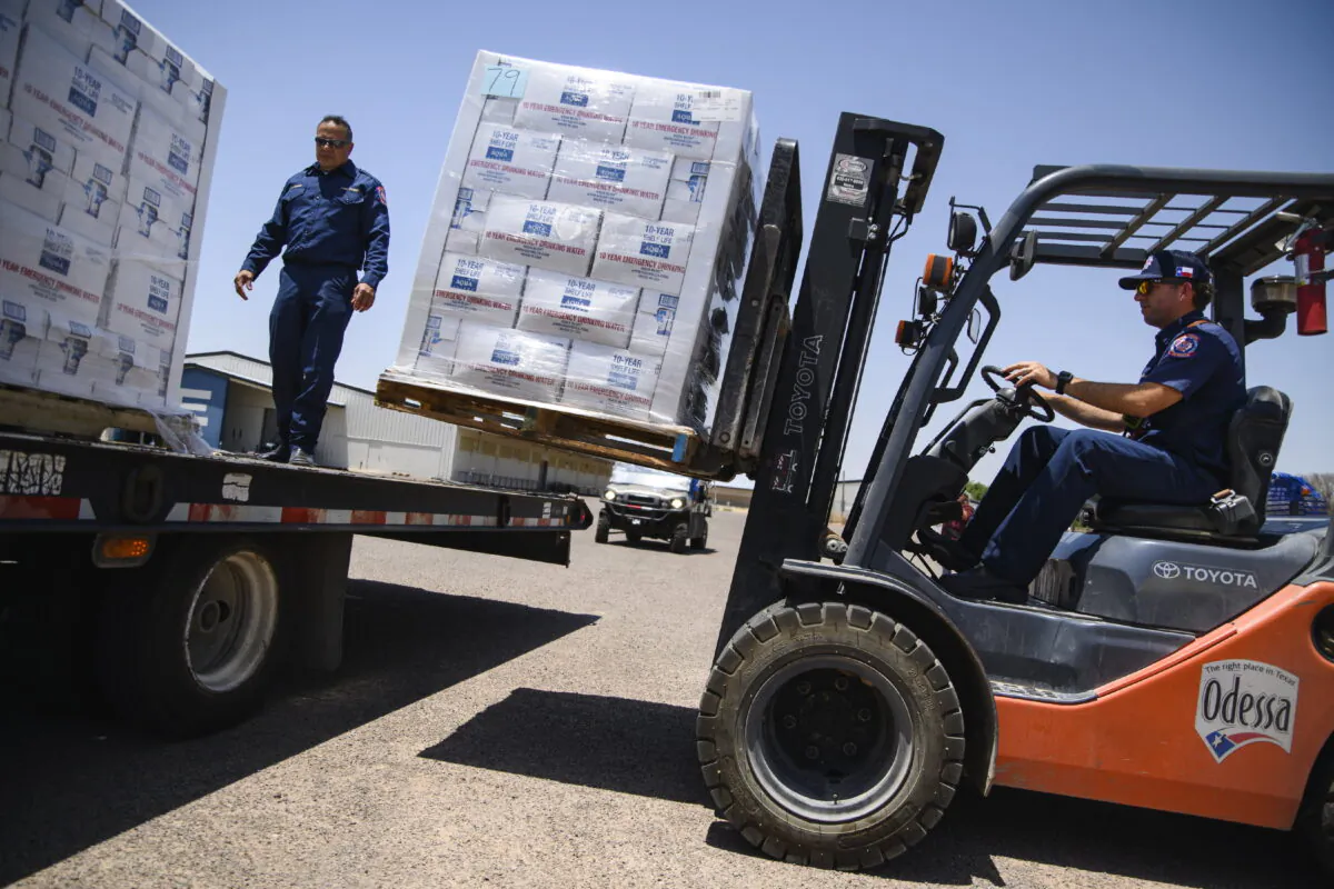 Odessa Fire Rescue Chief John Alvarez (L), and Central Station Captain Austin Yocham unload pallets of emergency drinking water as they help prepare to hand out cases of water for residents in need after a broken water main left the majority of Ector County without clean running water in Odessa, Texas on June 14, 2022. (Eli Hartman/Odessa American via AP)