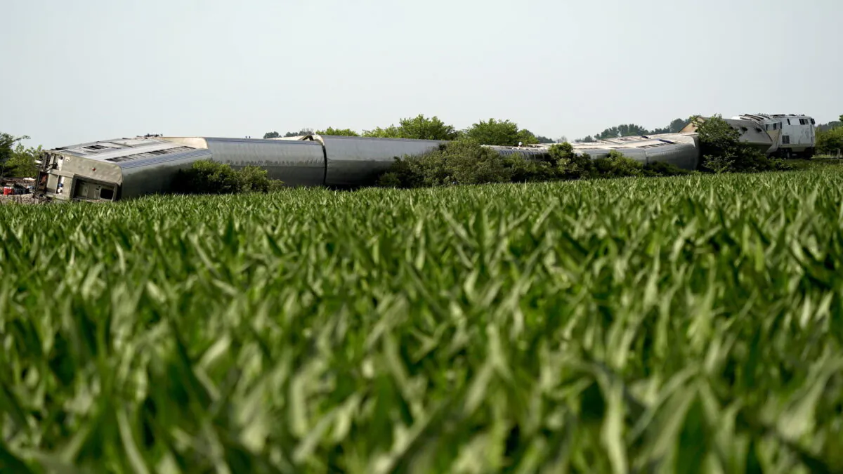 An Amtrak train which derailed after striking a dump truck is seen beyond a corn field near Mendon, Mo., on June 27, 2022. (Charlie Riedel/AP Photo)