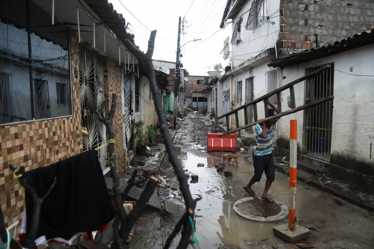 A man carries a ladder amid rubble from houses damaged by heavy rains, in the Coqueiral neighborhood, in Recife, Brazil, on May 31, 2022. (Diego Nigro/Reuters)