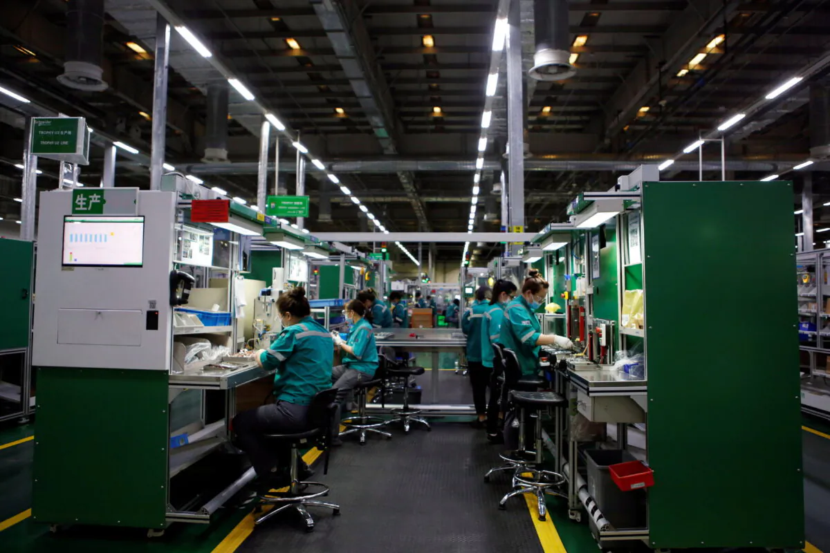Employees work on the production line during an organized media tour to a Schneider Electric factory in Beijing on Feb. 17, 2022. (Florence Lo/Reuters)