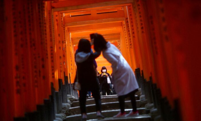 Visitors, wearing masks following the COVID-19 outbreak, explore the wooden torii gates at Fushimi Inari Taisha shinto shrine in Kyoto, Japan, on March 13, 2020. (Edgard Garrido/Reuters)