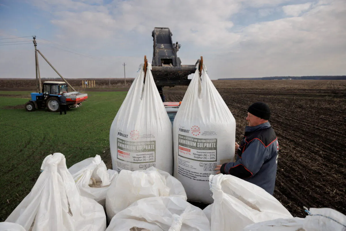 A local farm worker unloads Ukrainian-made fertilizer from a truck to use on a wheat field near the village of Yakovlivka after it was hit by an aerial bombardment outside Kharkiv, Ukraine, on April 5, 2022. (Thomas Peter/Reuters)