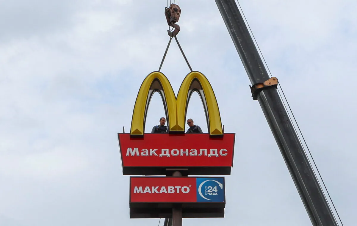 Workers use a crane to dismantle the McDonald's logo and signage from a drive-through restaurant of McDonald's in the town of Kingisepp, Russia, on June 8, 2022. (Anton Vaganov/Reuters)